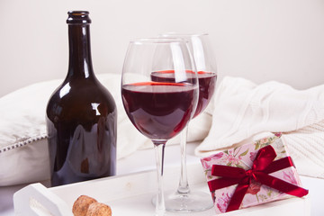 Two glasses with red grape wine with bottle and gift box on the background. Romantic dinner concept.