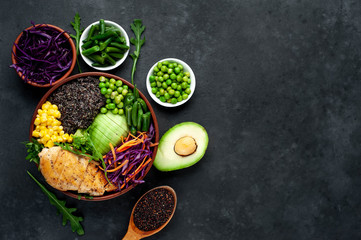 Obraz na płótnie Canvas Bowl Buddha.Quinoa, chicken breast, avocado, red cabbage, arugula, carrot, green peas, corn, broccoli, green beans in a plate on a stone background, with copy space for your text