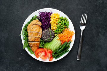 Bowl Buddha.Quinoa, chicken breast, arugula, avocado, red cabbage, carrot, green  peas, corn, tomato, green beans in a white plate on a stone background. with copy space for your text
