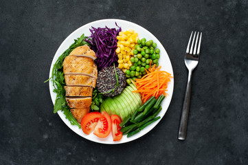 Obraz na płótnie Canvas Bowl Buddha.Quinoa, chicken breast, arugula, avocado, red cabbage, carrot, green peas, corn, tomato, green beans in a white plate on a stone background. with copy space for your text
