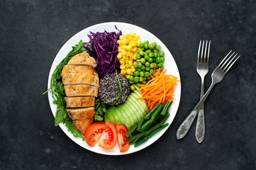 Bowl Buddha.Quinoa, chicken breast, arugula, avocado, red cabbage, carrot, green  peas, corn, tomato, green beans in a white plate on a stone background. with copy space for your text