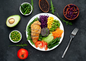 Bowl Buddha.Quinoa, chicken breast, arugula, avocado, red cabbage, carrot, green  peas, corn, tomato, green beans in a white plate on a stone background. with copy space for your text