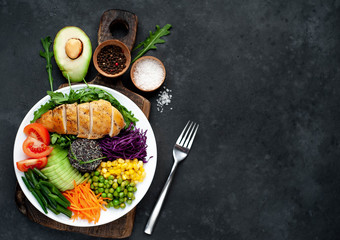 Bowl Buddha.Quinoa, chicken breast, arugula, avocado, red cabbage, carrot, green  peas, corn, tomato, green beans in a white plate on a stone background. with copy space for your text