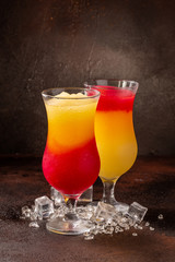 Delicious icy cocktail with fruits on dark grounge background. Healthy colorfull fruit shakes with ice on textured table.
