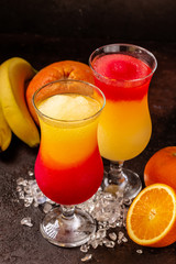 Delicious icy cocktail with fruits on dark grounge background. Healthy colorfull fruit shakes with ice on textured table.