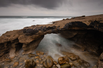 Fototapeta na wymiar Arch shaped rock formation in the coastline. Long exposure