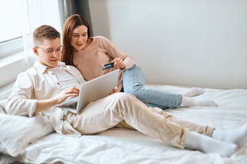 man and woman sitting with laptop, looking at the screen, holding credit card, close up photo, rest