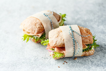 Fototapeta Two fresh sandwiches with ham, cucumbers, lettuce and onions on grey background. obraz