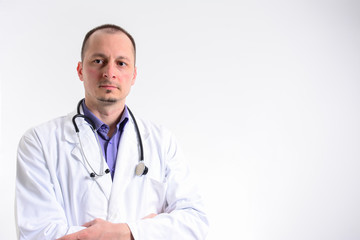 Male doctor with arms crossed and looking at camera while standing against white background. Caucasian male doctor with arms crossed.