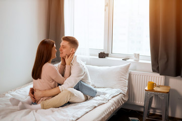 Obraz na płótnie Canvas young family enjoy togetherness and relaxation in bedroom. Relationship concept, free time, spare time, lifestyle, couple fell in love