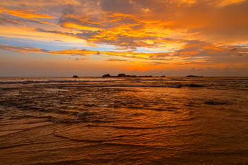 Fototapeta na wymiar Dramatic sunset sky with red yellow clouds over ocean in Sri Lanka island