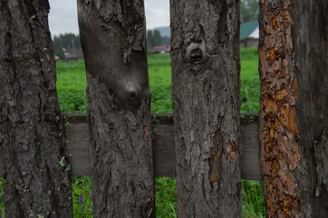  wooden fence in a moss near a summer Siberian field with potatoes