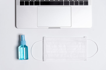 The equipment to protect COVID-19, white mask and hand cleaner gel before working in the office with laptop.