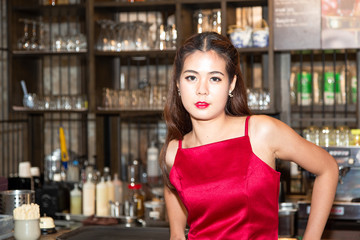 Young beautiful woman with red dress standing in front of the counter in a coffee shop after successful conference.