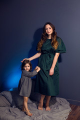 Obraz premium mother and daughter in dresses sitting on a bed in a bedroom