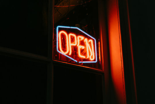 Red open neon sign glowing in the night.