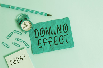 Handwriting text writing Domino Effect. Conceptual photo Chain reaction that causing other similar events to happen Alarm clock clips notepad blank crushed sheet marker sky colored background