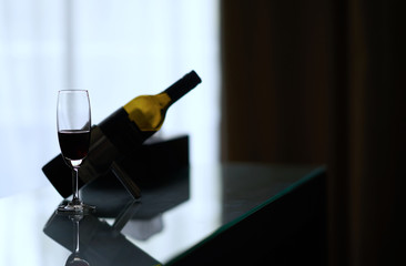 wine alcohol beverage in clear tall glass with bottle on table in contrast art drinks concept with copy space