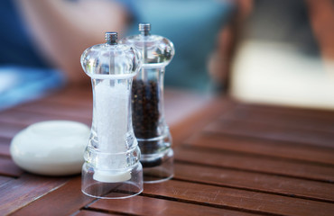Pepper and grained salt in transparent grider on table with copy space