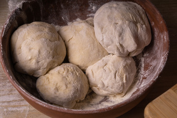 Balls of dough. Plywood cutting board, wooden flour sieve and wooden rolling pin - tools for making dough.