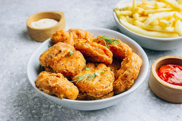 Fried crispy chicken nuggets with french fries and ketchup on light gray background. Seletive focus