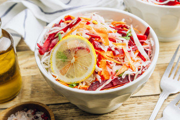 Spring healthy vegan salad with raw beet, carrot and cabbage in white bowls. Alkaline Diet concept. Selective focus