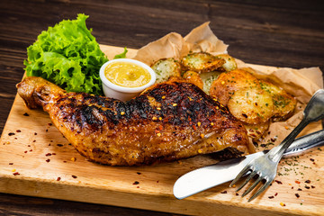Barbecue chicken thigh with baked potatoes on cutting board