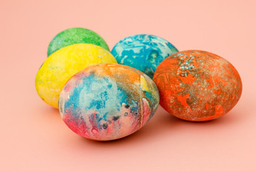 Four multi-colored Easter eggs on pink background top view, space for text. Concept happy easter day.