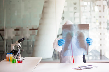  Microbiologists or doctors are testing a sample of biological tubes contaminated by Corona-virus Covid 19 in a laboratory with a biological tube for analysis and and film samples of infected lung