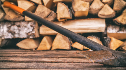 An old rusty axe stands against the woodpile