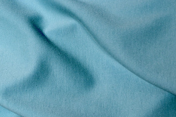 Turquoise textile. The material folds randomly on a horizontal surface. Fabric sample.