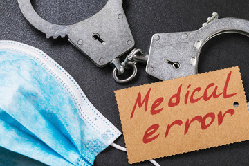Handcuffs and a medical mask on the table, top view. Medical error concept