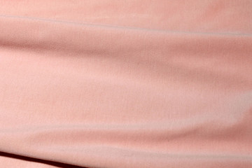 Textile in color salmon. The material folds randomly on a horizontal surface. Fabric sample.