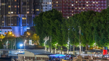 Fototapeta premium Seine river with ship in Paris at night timelapse, waterfront of the seine river in the city of Paris in france