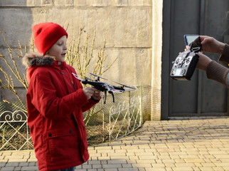  Family leisure. A boy in a red jacket and hat in the fresh air launches a drone.