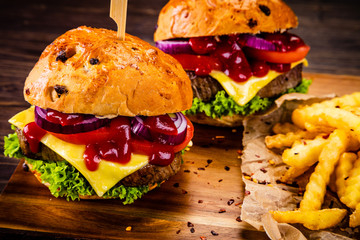 Big hamburgers and french fries on wooden board