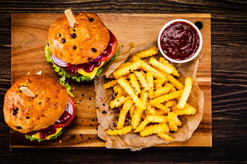 Big hamburgers and french fries on wooden board