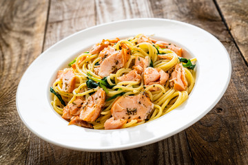 Pasta with salmon and spinach on wooden background