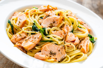 Pasta with salmon and spinach on wooden background