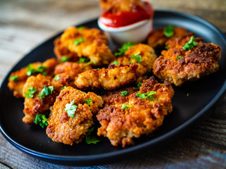 Fried chicken nuggets with ketchup on wooden table