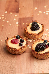 Healthy cereals muffins with berries and yellow cream on the wooden desk.