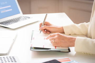  Close-up of businesswoman's hand while making note on the notebook