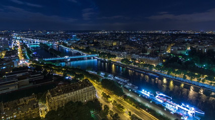Naklejka premium Aerial Night timelapse view of Paris City and Seine river shot on the top of Eiffel Tower