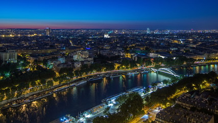 Fototapeta premium Aerial Night timelapse view of Paris City and Seine river shot on the top of Eiffel Tower