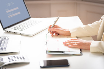 Fototapeta premium Close-up of businesswoman's hand while making note on the notebook