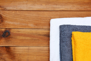 Spa soft towels of diffent color on wooden background with copyspace