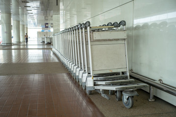 Closeup row of empty steel trolley for carrying luggage parking at the airport