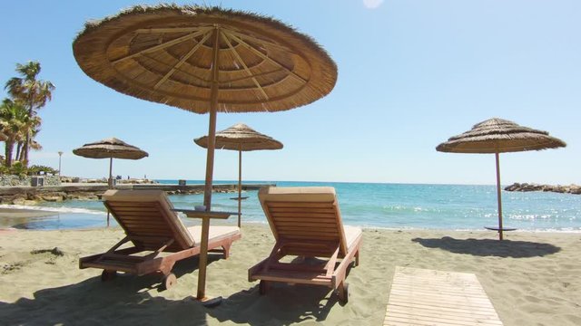 Sun lounger and beach umbrellas. Luxury resort on the beach. Beautiful sea, palm trees and sand.