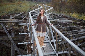 Obraz na płótnie Canvas girl in vintage dress stands on a bridge