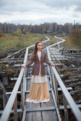 girl in vintage dress stands on a bridge
